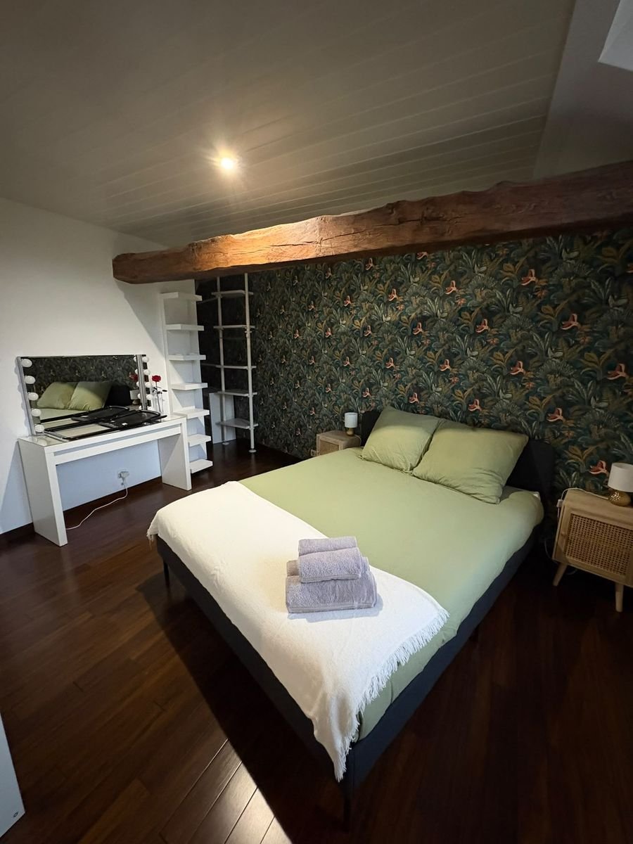 Chambre avec poutre apparente et papier peint végétal